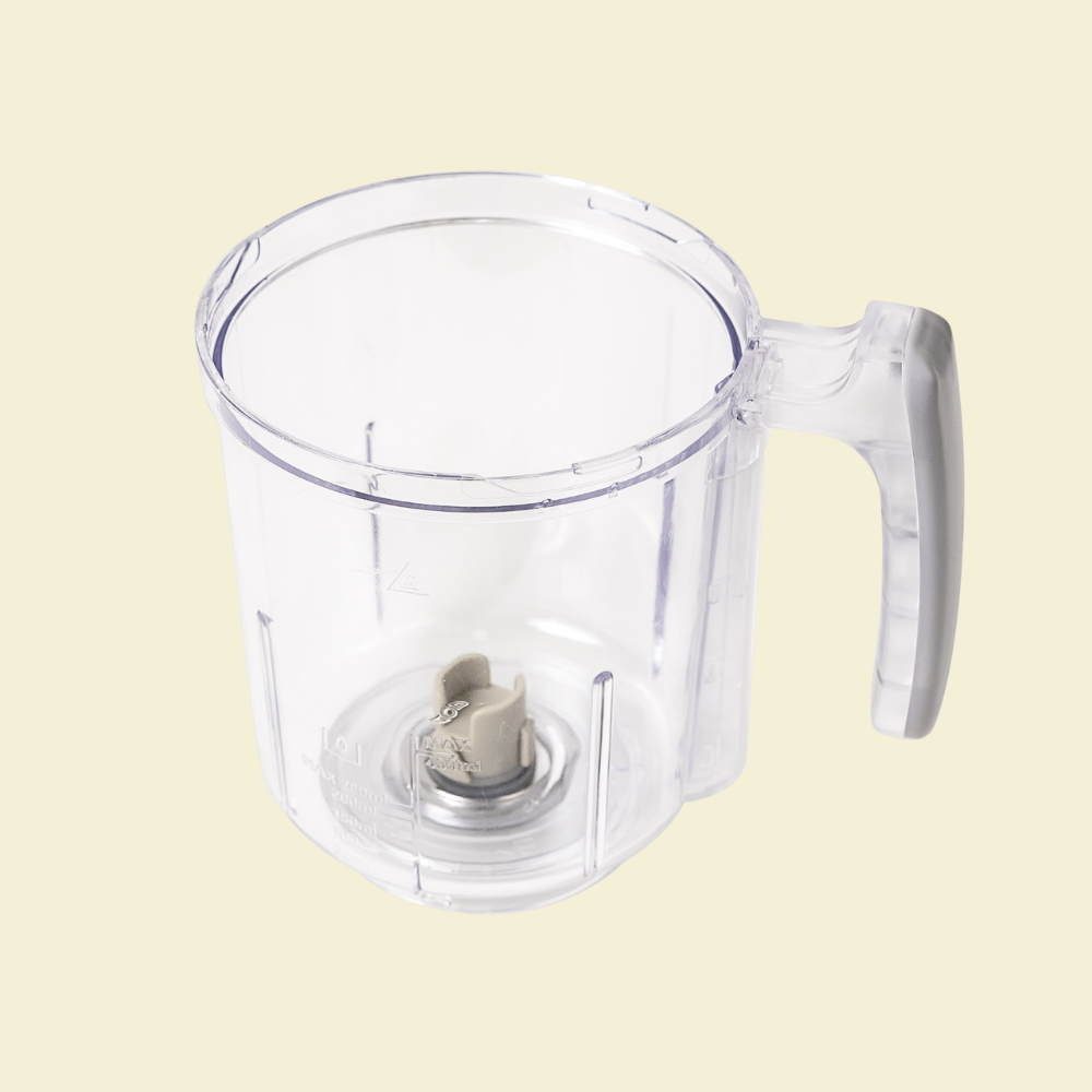 Clear plastic blender container with handle on a beige background